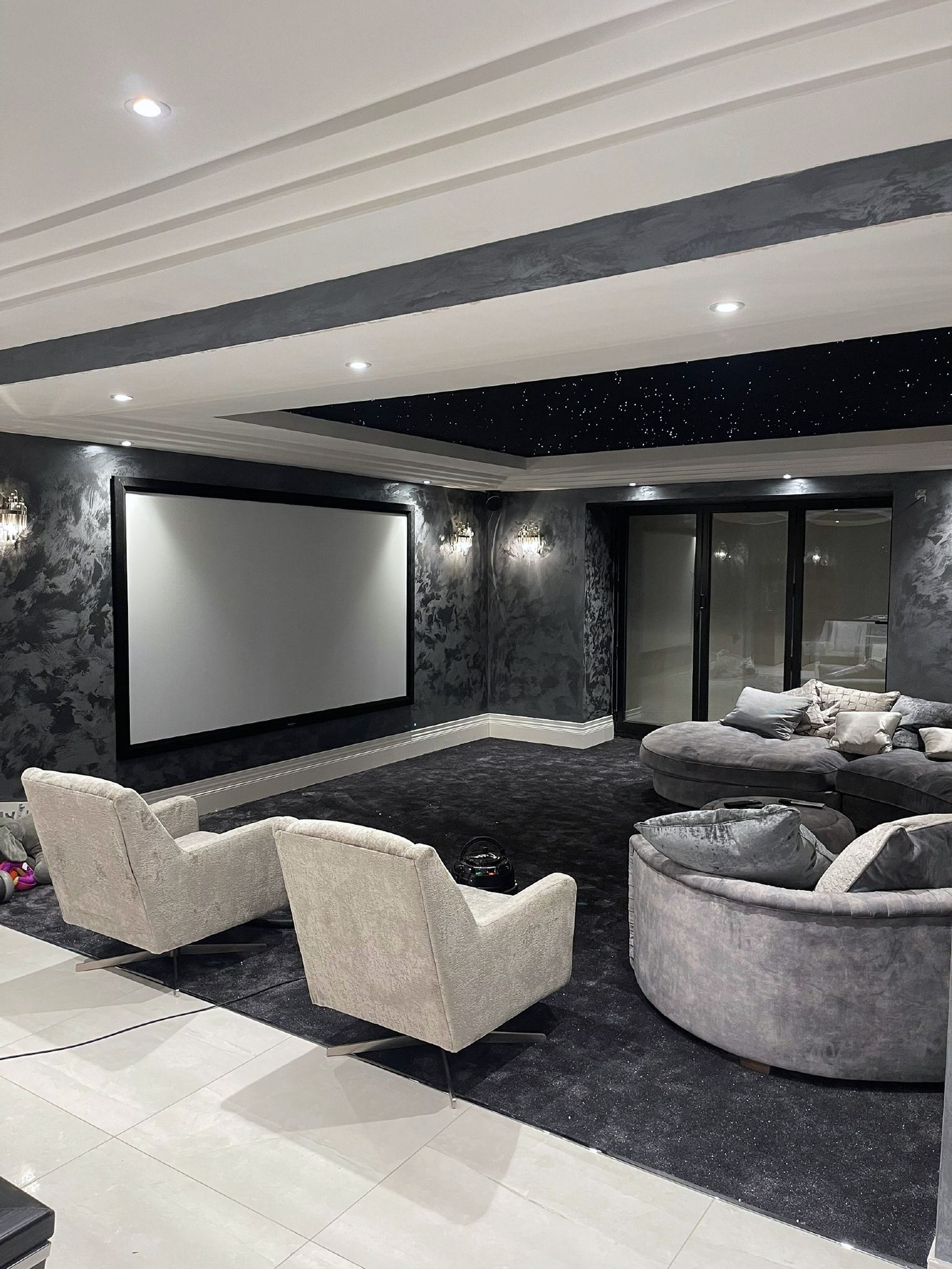 Cinema room with grey armchairs facing a large screen