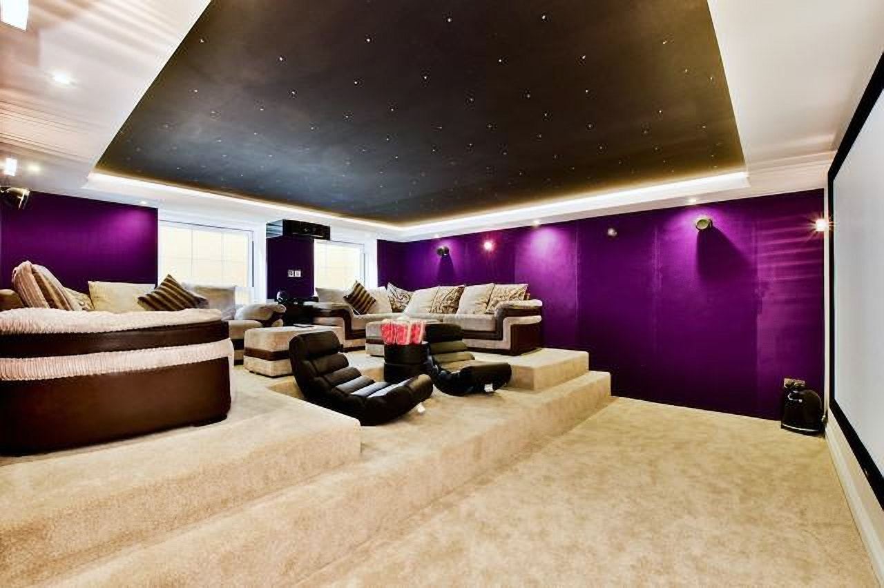 Tiered cinema room with purple walls and reclining seats