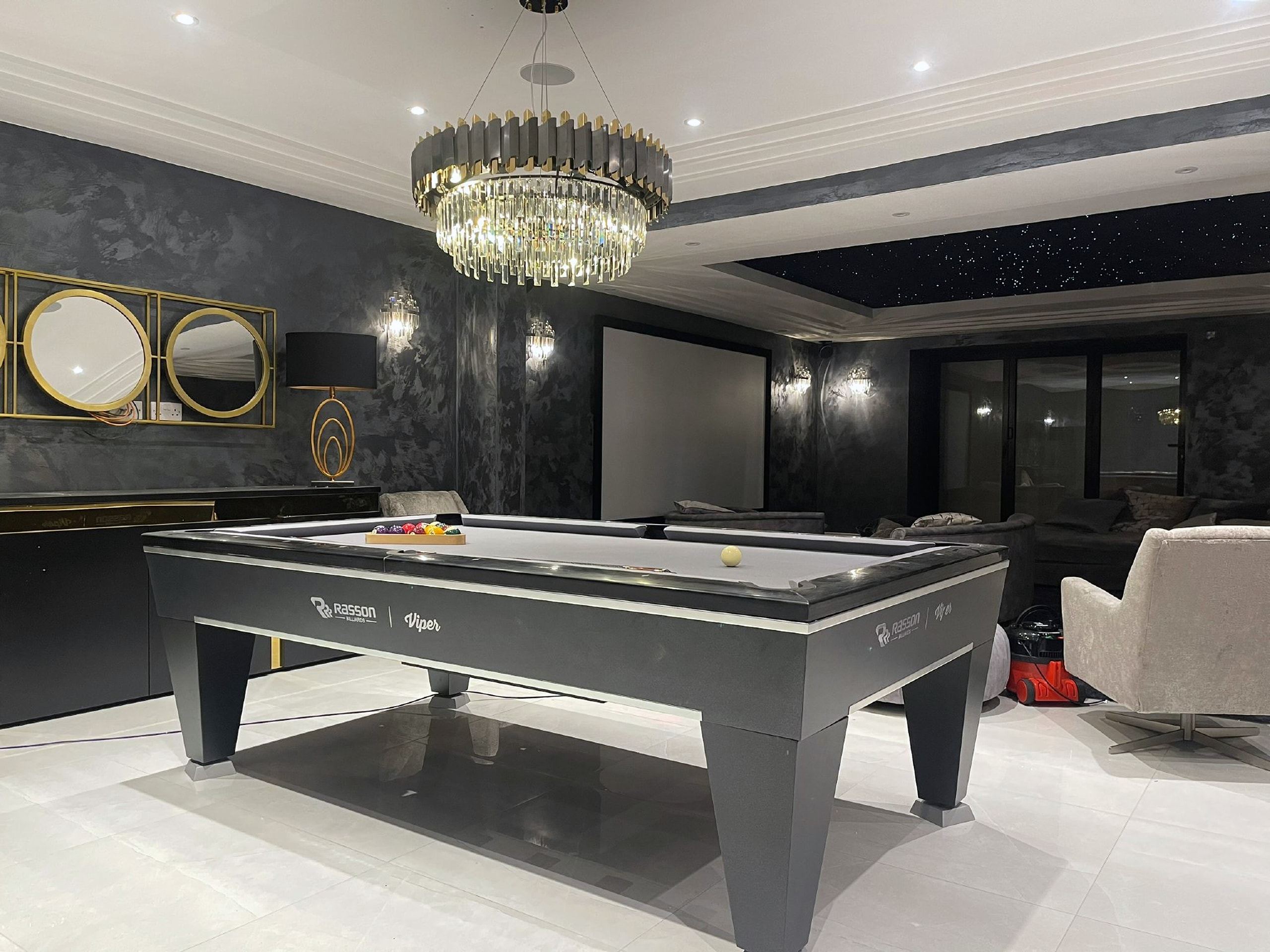 Basement games room with a pool table beneath a crystal chandelier