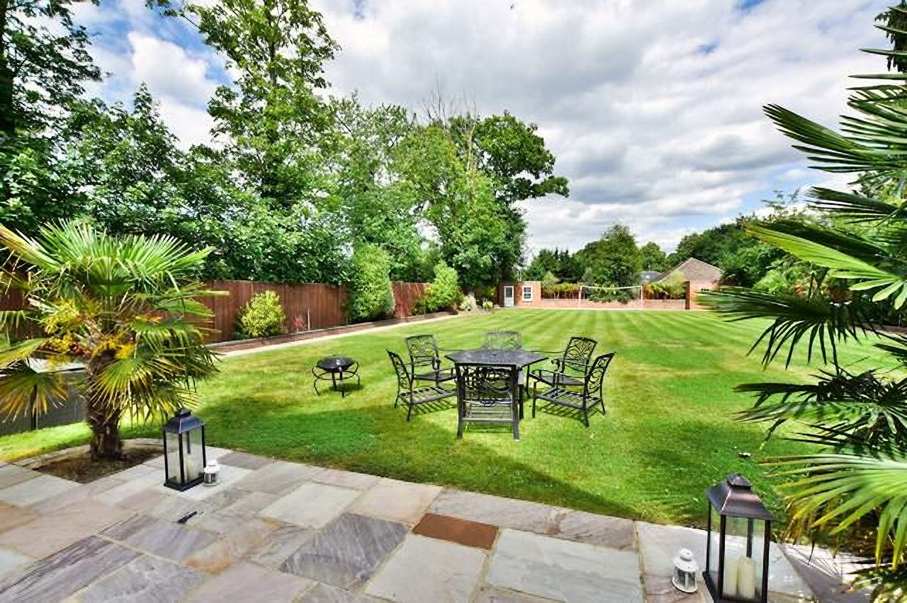 Stone patio with outdoor dining beside a large lawn