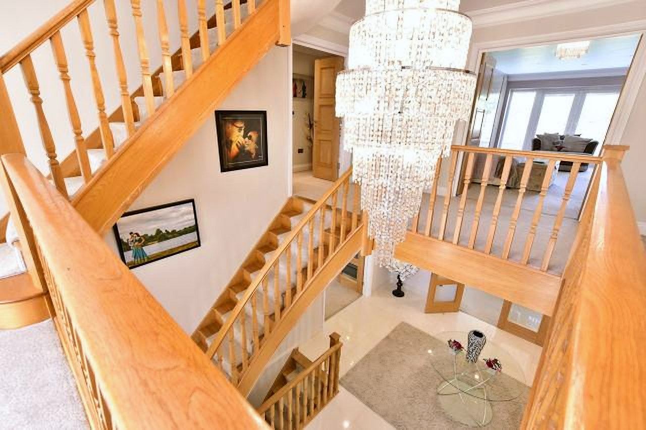 Oak staircase rising around a crystal chandelier